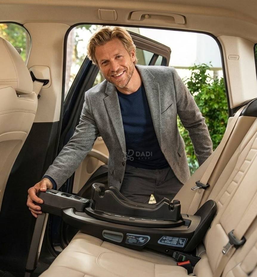 Instalacja bazy ISOFIX w samochodzie przez mężczyznę w marynarce. Widać mechanizm mocowania